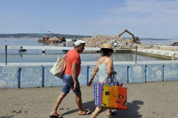 Turisti u Crikvenici promatraju radove na dogradnji i rekonstrukciji Zapadnog lukobrana / Snimio Roni BRMALJ