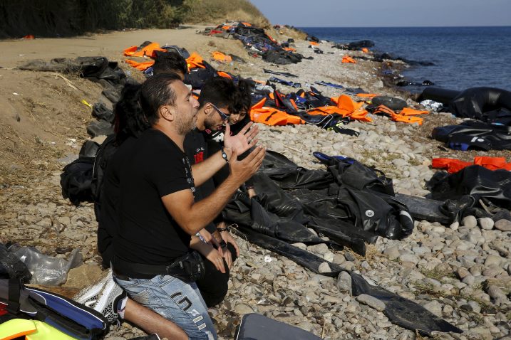 Molitva Sirijaca nakon što su morem iz Turske sigurno stigli na grčku obalu  Foto REUTERS